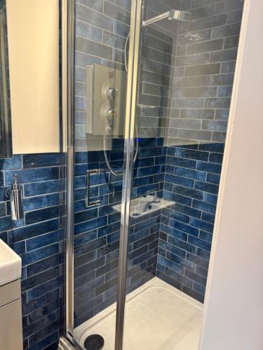 a bathroom with a shower with blue tiles at The London Inn in Padstow