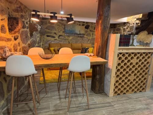 a dining room with a wooden table and white chairs at Casa da Barragem in Negrões
