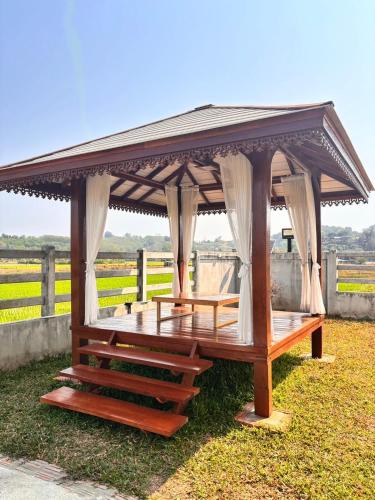 a wooden gazebo with a roof on the grass at Baan Marukome Chiang Rai บ้านมารุโกเมะ เชียงราย in Ban Pa Yang (3)