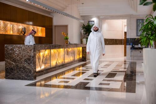 two men in white walking through a lobby at Swissotel Al Maqam Makkah in Makkah
