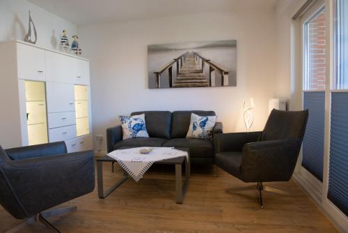 a living room with a couch and chairs and a table at Deichnähe A in Norden
