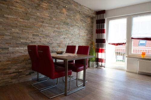a dining room table with red chairs and a brick wall at Bounty in Norden