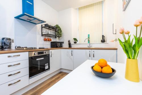 a white kitchen with a bowl of oranges on a counter at jaysapartment III in Aberdeen