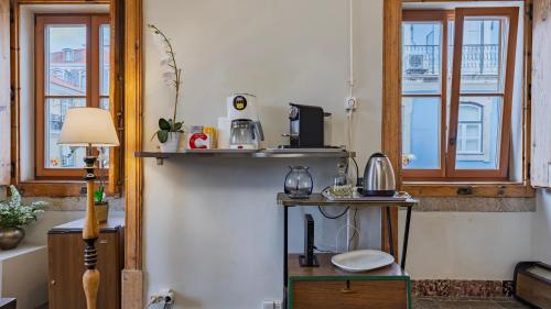 a room with a table and a shelf with a microwave at Portuguese Charm Guesthouse by LovelyStay in Lisbon