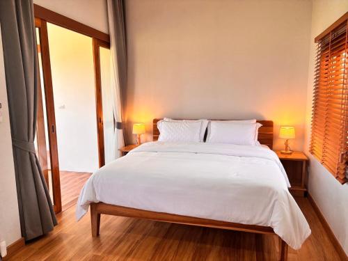 a bedroom with a large bed with white sheets and pillows at Baan Marukome Chiang Rai บ้านมารุโกเมะ เชียงราย in Ban Pa Yang (3)