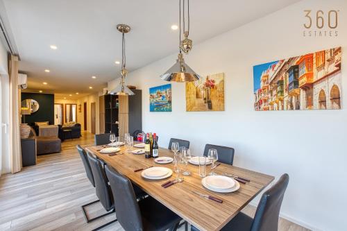 a dining room with a long wooden table and chairs at Beautiful 3BR designer home with WIFI, AC and Balcony in Il-Ħamrija