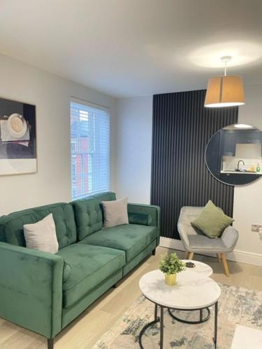 a living room with a green couch and a table at Brand New City Centre Apartment - Free offsite Parking Available in Nottingham