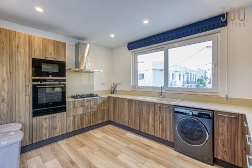 a kitchen with wooden cabinets and a washer and dryer at Beautiful 3BR designer home with WIFI, AC and Balcony in Il-Ħamrija