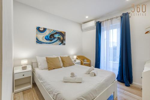 a bedroom with a large white bed with blue curtains at Beautiful 3BR designer home with WIFI, AC and Balcony in Il-Ħamrija