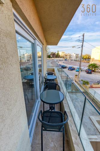 a balcony with two tables and a view of a street at Beautiful 3BR designer home with WIFI, AC and Balcony in Il-Ħamrija