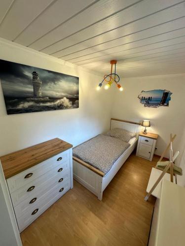 - une chambre avec un lit, une commode et un phare dans l'établissement Ferienhaus Küstenkracher in Maasholm-Bad, à Maasholm-Bad