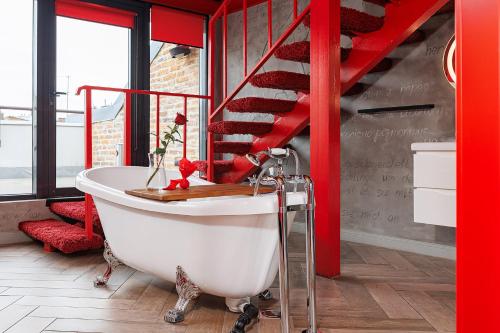 a red staircase in a bathroom with a bath tub at Masoch. Hotel & Cafe in Lviv