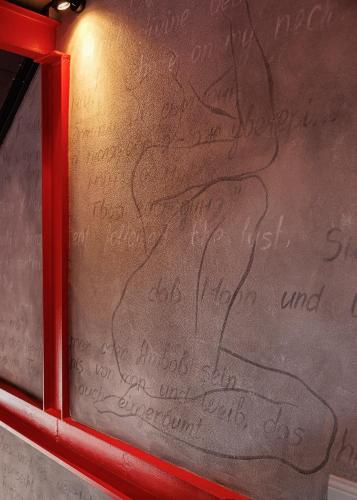 a wall with writing on it with a red frame at Masoch. Hotel & Cafe in Lviv