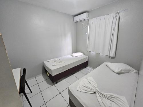 a small room with two beds and a window at Ok Inn Hotel Criciúma Centro in Criciúma
