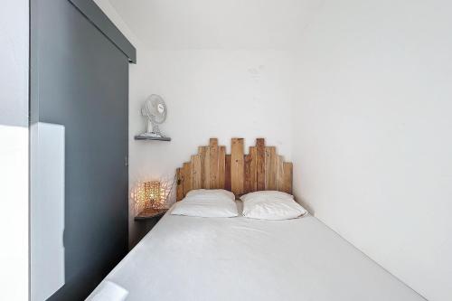 une chambre avec un lit blanc avec une tête de lit en bois dans l'établissement Le Graziot - Appartement face à l'étang du Grazel, à Gruissan