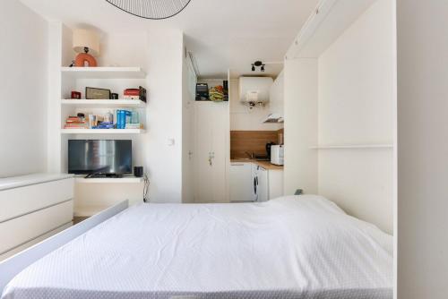 - une chambre avec un lit blanc et des armoires blanches dans l'établissement Charming studio Paris Levallois Perret, à Levallois-Perret
