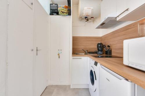 une cuisine blanche avec des armoires blanches et un évier dans l'établissement Charming studio Paris Levallois Perret, à Levallois-Perret