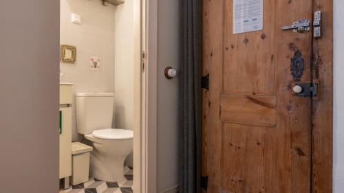 a bathroom with a toilet and a wooden door at Portuguese Charm Guesthouse by LovelyStay in Lisbon