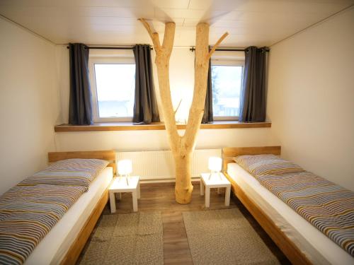 two beds in a room with a tree in the middle at Albsteig-Apartments Gruibingen in Gruibingen