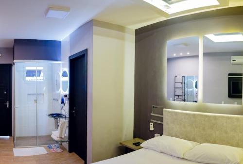 1 dormitorio con cama, espejo y baño en Pousada e Motel RV, en Santa Maria