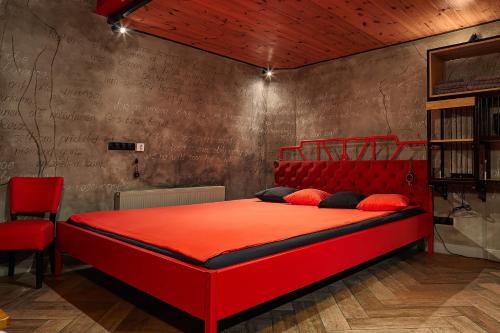 a red bed with red pillows in a room at Masoch. Hotel & Cafe in Lviv