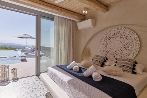 a bedroom with a large bed with a view of a patio at Aegean Sunset Villas & Spa 'Villa Sky' in Skouloúfia