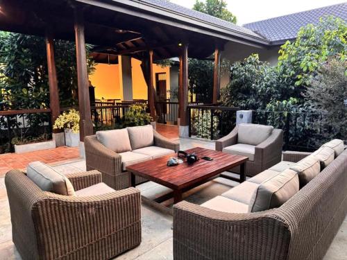 a patio with couches and a wooden table and chairs at Birders Urban Retreat in Sri Jayewardenepura Kotte