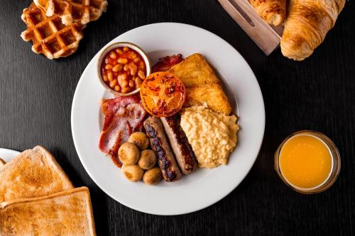 a plate of breakfast food with eggs bacon beans and bread at Village Hotel Nottingham in Nottingham
