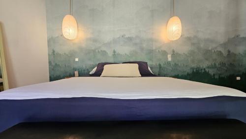 a bedroom with a large bed with two lights at Maison d 'ô in Saint-Philippe