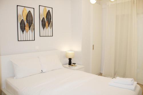 a bedroom with a white bed with three pictures on the wall at ARIS Piraeus- Sailor's friend in Piraeus