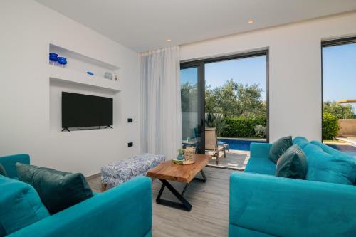 a living room with blue couches and a tv at AKEA VILLAS in Tragaki