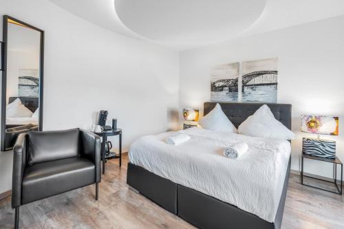 a bedroom with a bed and a black chair at Urban Retreat Apartment - Whirpool - Top Lage in Cologne