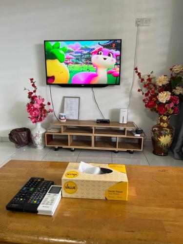 a remote control sitting on a table in front of a tv at TCH Alor Setar Homestay in Alor Setar