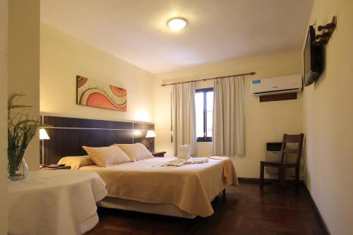 Una habitación de hotel con dos camas y una ventana. en Hotel Sierralago, en Villa Carlos Paz