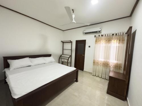 un dormitorio con una cama y una ventana en Minhas Villas, en Kamburugamuwa