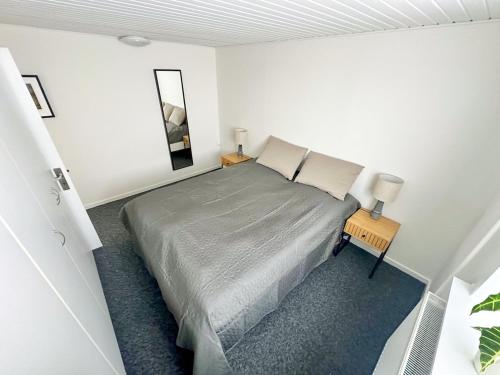 a white bedroom with a bed and a mirror at City Center Modern 2-BR Haven with a Stylish Twist in Aalborg