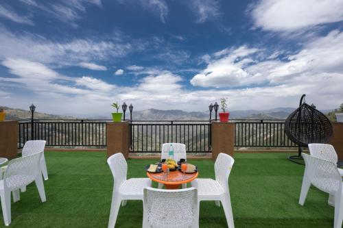 a patio with white chairs and a table with fruit on it at The Yoga Retreat l Place for Yoga I Meditation I Shanti & Dhayan l Vacations I Family Events I Kufri by Exotic Stays in Shimla