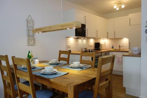 a kitchen with a wooden table and chairs in a kitchen at Eckhus in Nieblum