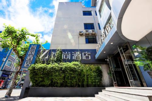 a building with a bush in front of it at Zsmart智尚酒店上海南京西路梅陇镇广场店 in Shanghai