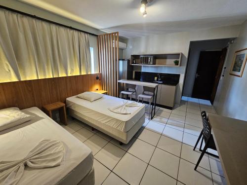 a hotel room with two beds and a kitchen at Ok Inn Hotel Criciúma Centro in Criciúma