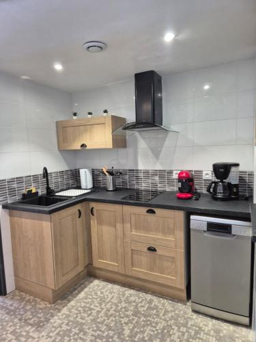 une cuisine avec des placards en bois et des comptoirs noirs dans l'établissement Appartement au pied des pistes, Les jouvencelles, à Prémanon