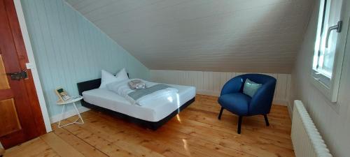 a small bedroom with a bed and a blue chair at Refugio Heiligkreuz in Hasle