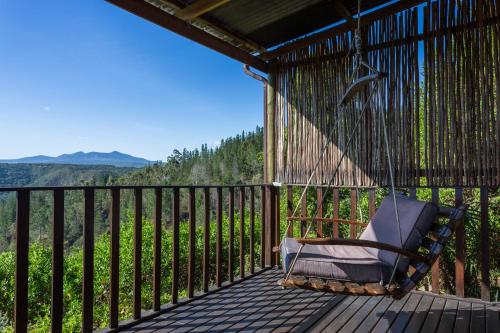 a rocking chair on a porch with a view at Forest Valley Cottages in Knysna