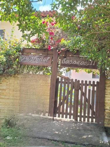 a wooden gate with flowers on a brick wall at RS1- casa andar superior para até 8 pessoas praia do sossego itamaracá PE in Itamaracá