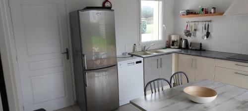 Il comprend une cuisine équipée d'un réfrigérateur et d'une table avec des chaises. dans l'établissement La Métairie, à Pléneuf-Val-André