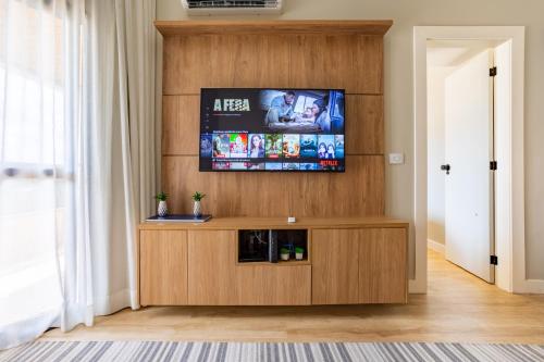 - un salon avec une télévision à écran plat sur un mur en bois dans l'établissement Bonaparte - 803 - Espetáculo - Recém Reformado - By Hospede Fácil, à Brasilia