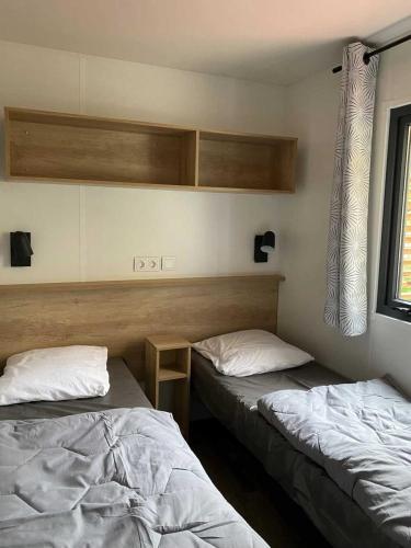 une chambre avec deux lits et une fenêtre dans l'établissement Camping 4 étoiles - Parc aquatique - ccb0bcc, à Saint-Sauveur