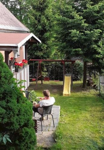 a man sitting in a chair in a yard at Chalupa Pod Návsí - Olešnice v Orlických horách in Olešnice v Orlických horách