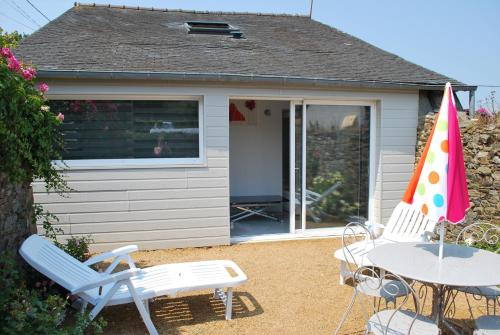 un patio avec une table, des chaises et un parasol dans l'établissement Gîte de SAINT RIOM, à Paimpol