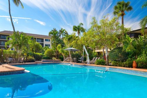 a large blue swimming pool with palm trees and a building at Best Western Naples Inn & Suites in Naples